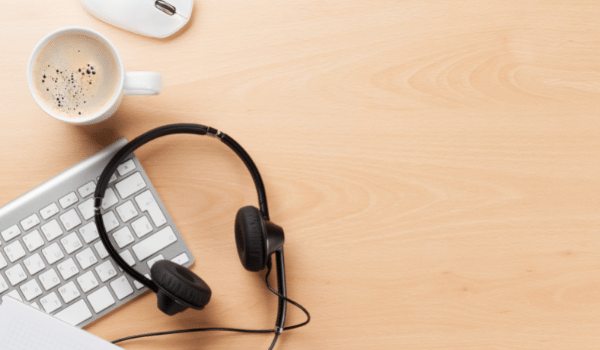 computer keyboard and headset on a desk with a cup of coffee